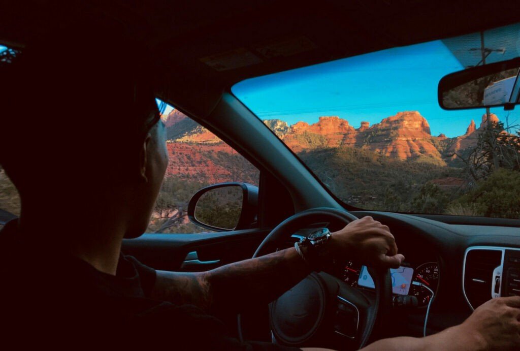 Mirando desde el lado del conductor del parabrisas de un automóvil a las hermosas rocas rojas contra el cielo azul claro mientras buscan un campamento disperso libre Sedona, AZ.