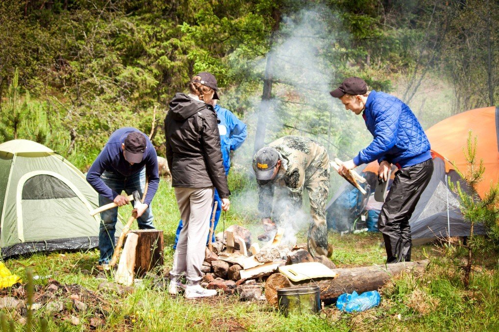 Los campistas de tiendas de campaña establecen un campamento y comienzan a encender un fuego con herramientas de supervivencia.
