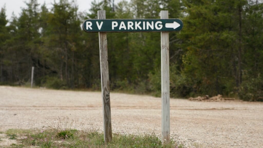 Un letrero de madera indica dónde hay espacios de estacionamiento para vehículos recreativos en un campamento.