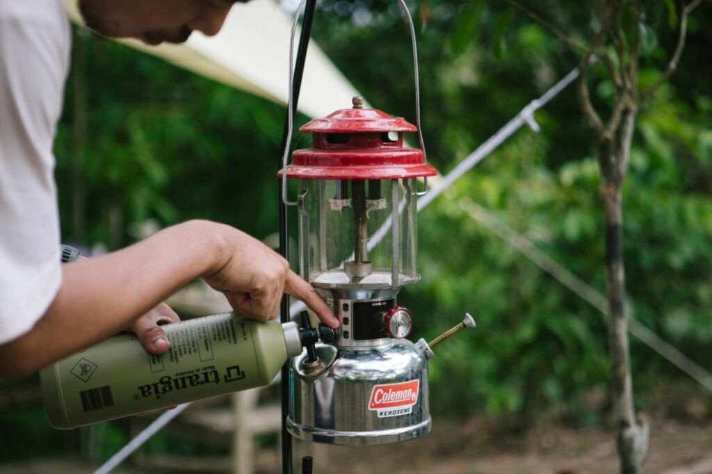 Un campista llena una lámpara de queroseno Coleman para iluminar su campamento.