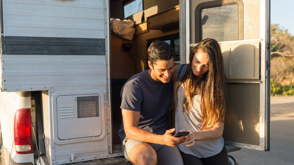 Una pareja usa aplicaciones para determinar dónde acampar a continuación en su camioneta.
