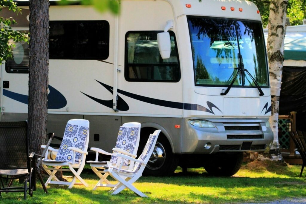 Una caravana aparcada en un camping con tumbonas delante de la puerta.