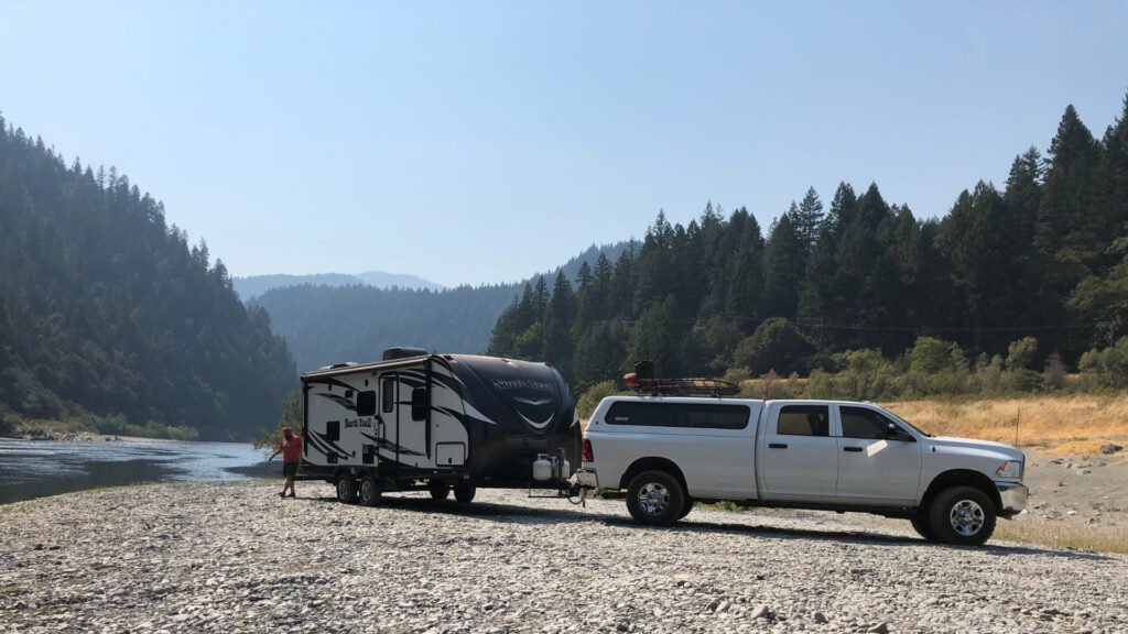 Un camión y un remolque para vehículos recreativos yacen en la orilla de un río donde no tienen que preocuparse por otros campistas.
