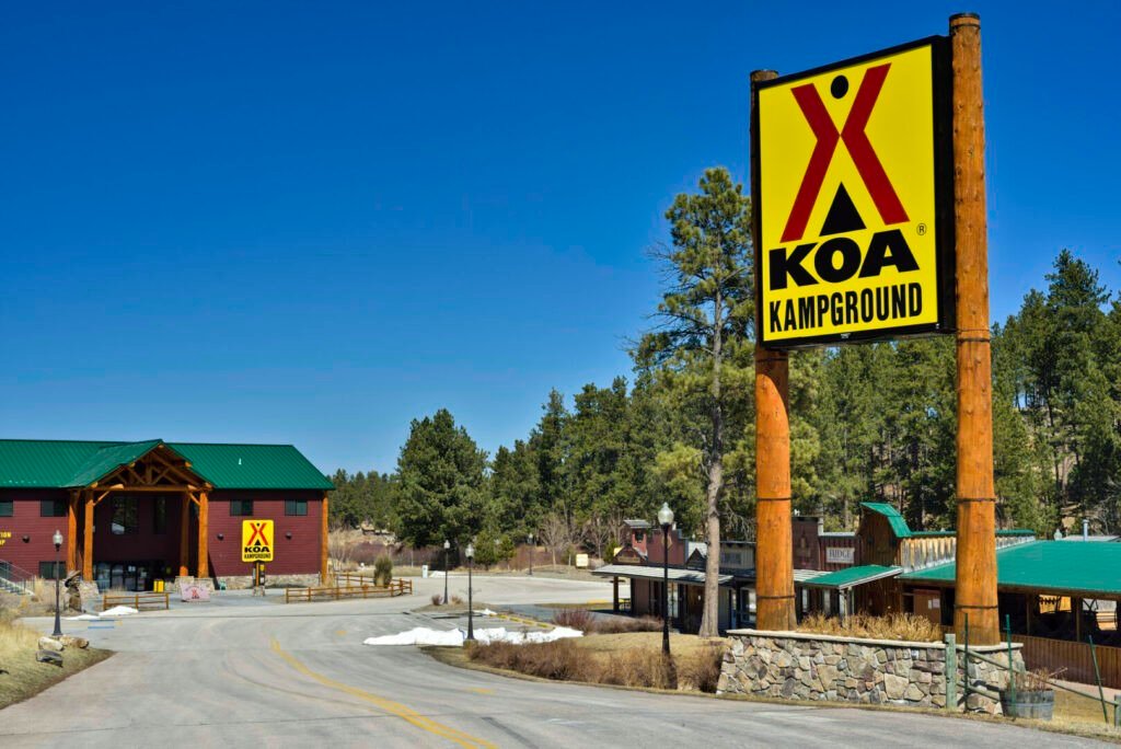 Un cartel de camping KOA amarillo brillante frente a un edificio de madera