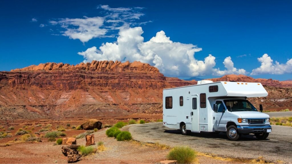 Un RV estacionado al lado de una carretera con rocas rojas de Moab Utah en el fondo