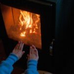 Una persona que pone sus manos cerca de su estufa de leña RV para mantenerse caliente