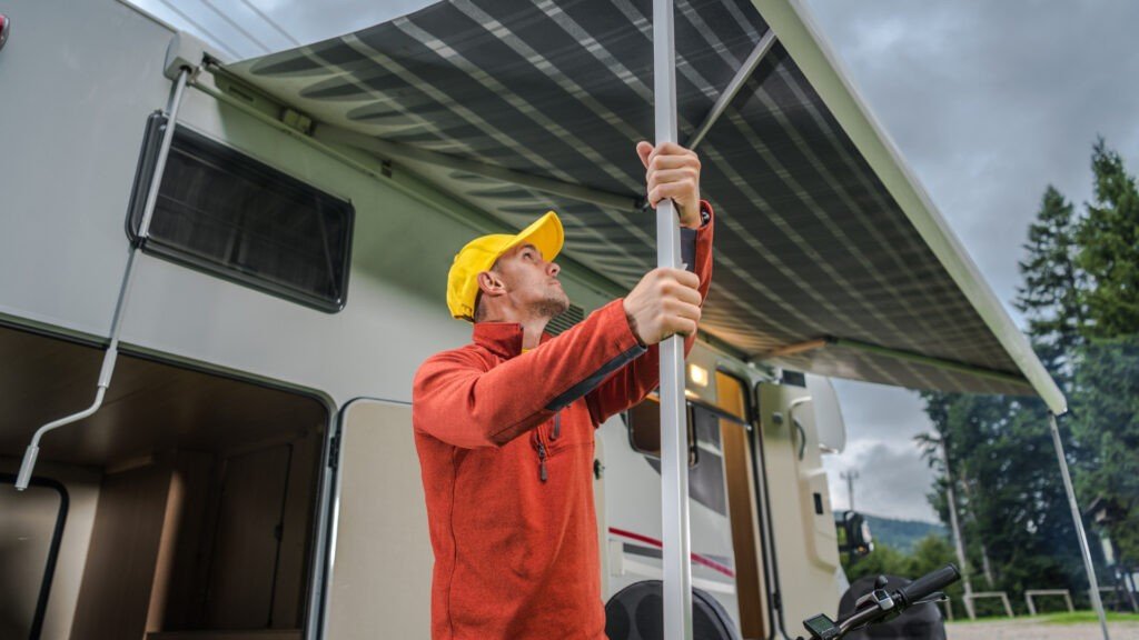 Un hombre instalando su toldo eléctrico.