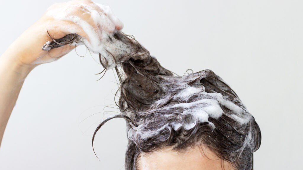 Una persona que se lava el cabello después de averiguar cómo quitar el olor a humo del cabello