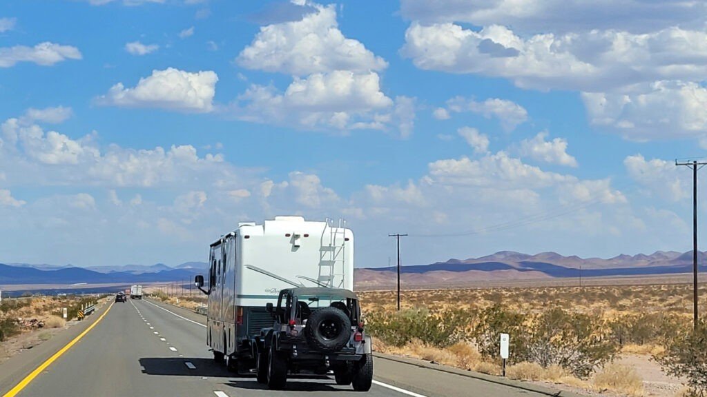 Una caravana con un jeep detrás de él en el camino