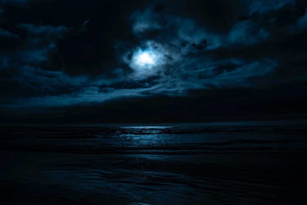 Moonlight shining over a body of water at night, gently illuminating the water ripples.